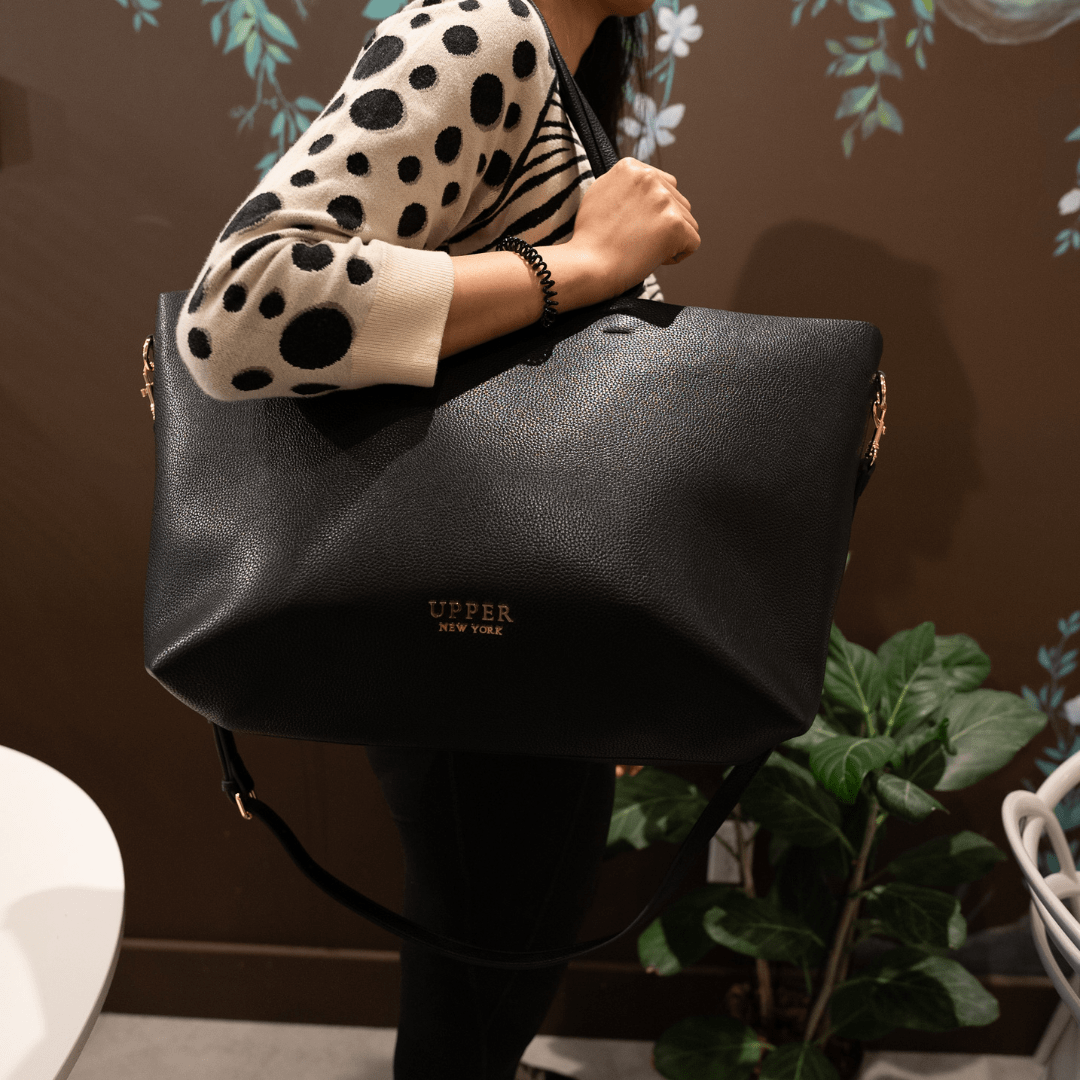 Carry-on tote in black worn on the shoulder by a mom heading to work