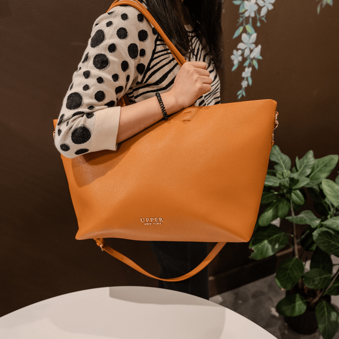 Carry-on tote in tan worn on the shoulder by a mom on a workday