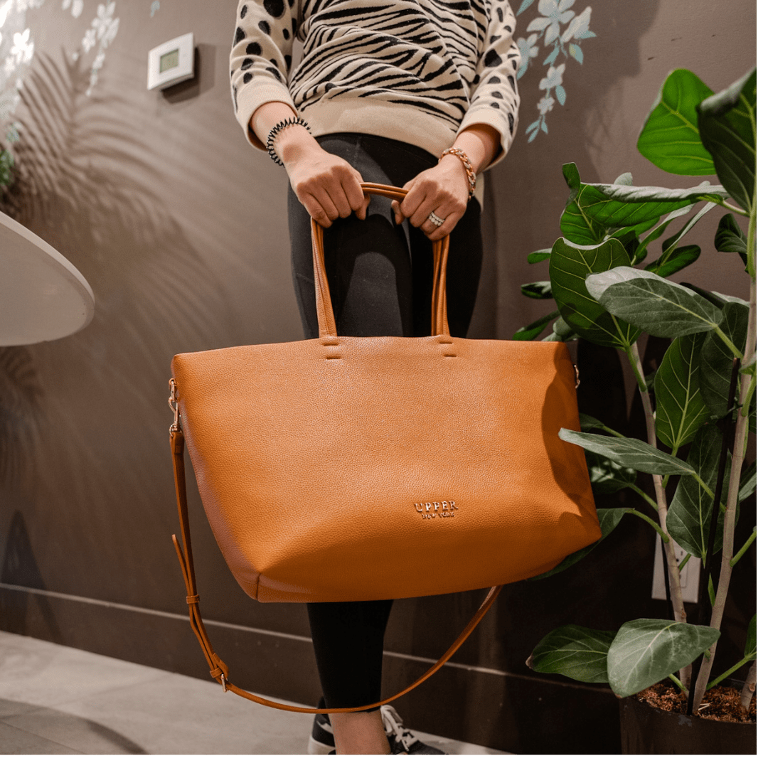 Carry-on tote in tan held with both hands by a mom