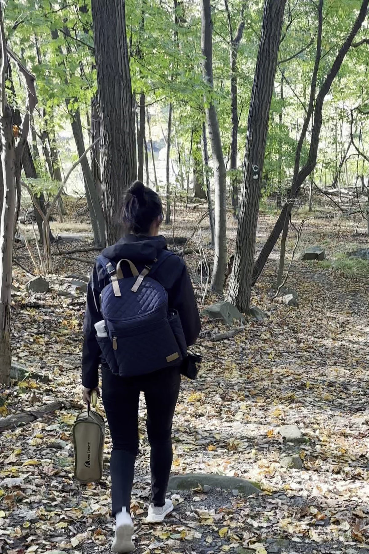 Parent wearing the Maison Air backpack on a walk in the woods
