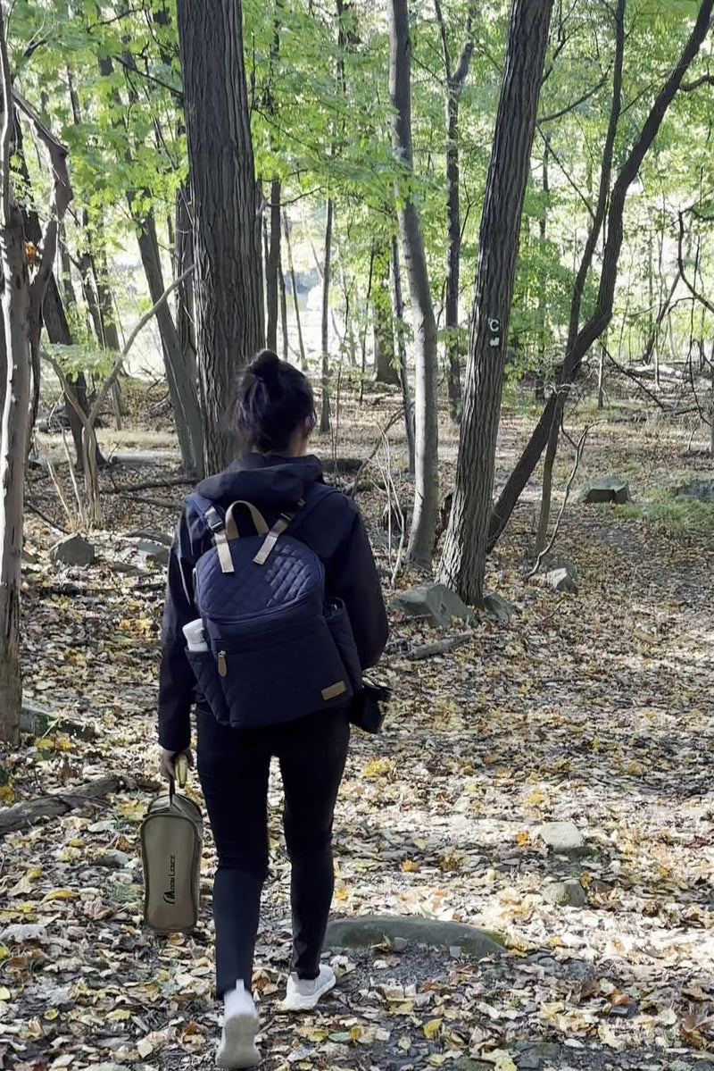 Parent wearing the Maison Air backpack on a walk in the woods