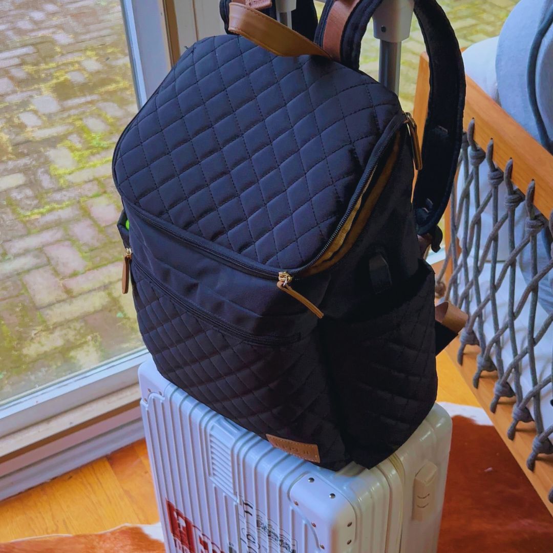 Maison Air backpack in black sitting on a carry-on suitcase