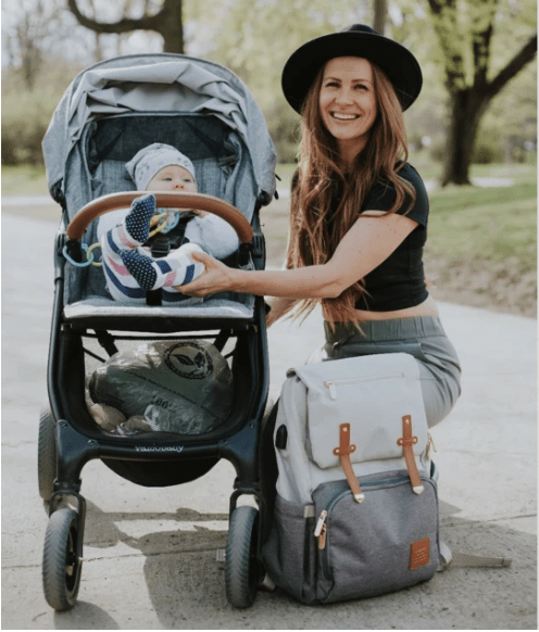 Milan everyday parent backpack beside a mom and her baby in a stroller at the park
