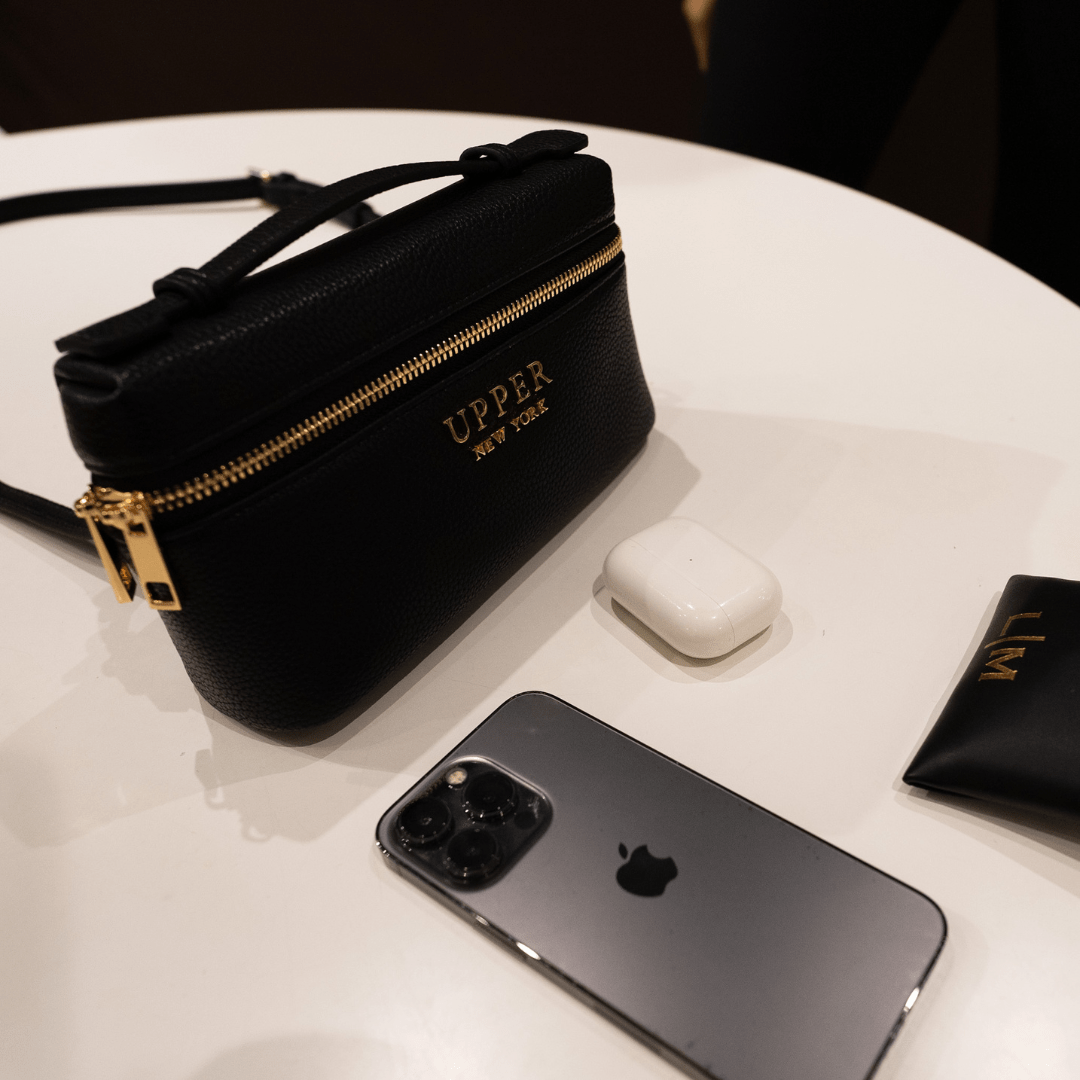 Mini bag in black on a table with a phone and earbuds, ready for a night out