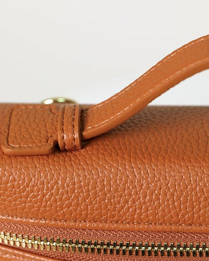 Mini crossbody bag in caramel, close-up of the pebbled grain, stitching and gold zip